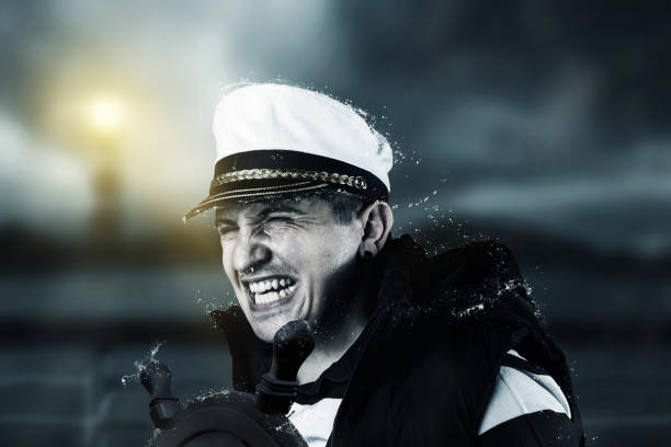 helmsman with vest and cap struggle against storm in front of blurred coast and light tower