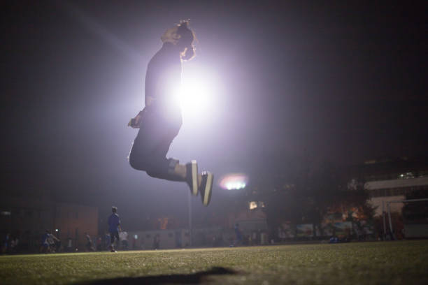 Football players watching young man about to kick football mid-air during match on football pitch.