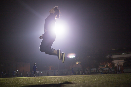 girl jump into the sky with floodlight behind