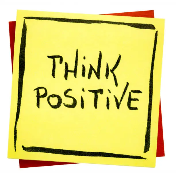 Think positive inspirational reminder - handwriting on an isolated sticky note