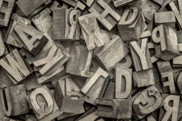 alphabet abstract - background of random letterpress wood type printing blocks, top view, black and white platinum toned image