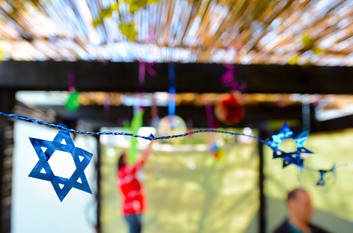 Jewish family decorating a Sukkah for the Jewish festival of Sukkot. A Sukkah is a temporary structure where meals are taken for the week.