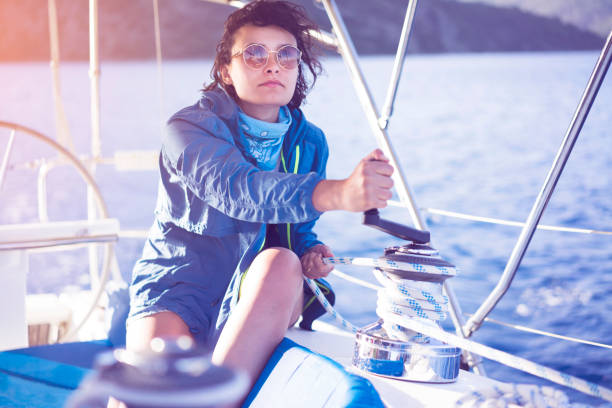 marin de jeune femme corde d’enroulement sur le treuil de voile - rope rigging nautical vessel day photos et images de collection