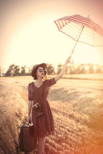 молодая женщина с зонтиком и чемоданом - vogue 40th стоковые фото и изображения
