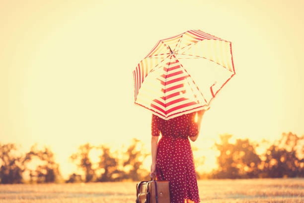 молодая женщина с зонтиком и чемоданом - vogue 40th стоковые фото и изображения