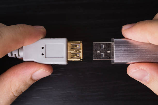 istock Silvery usb flash drive on a black desk and usb cable for connection close-up. A metal flash drive for storing memory in the hand on a dark background with hard light. 688314726
