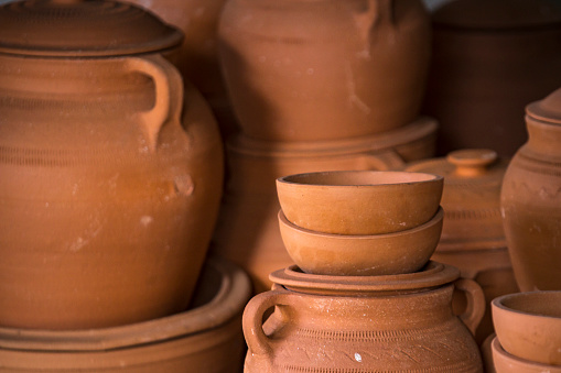 Many clay dishes stacked for sale, pots and bowls alike