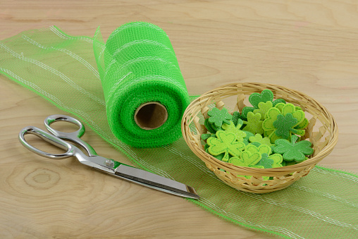 Saint Patrick's Day crafting project with scissors, shamrocks and ribbon on wood table