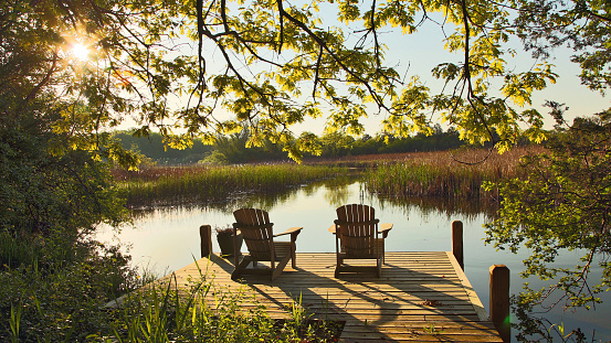 Escena del lago tranquilo con dos sillas de Adirondack photo