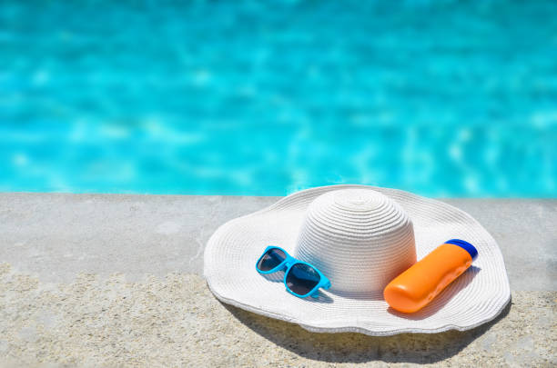 istock Summer hat, sunglasses and sunscreen near the pool 688335480