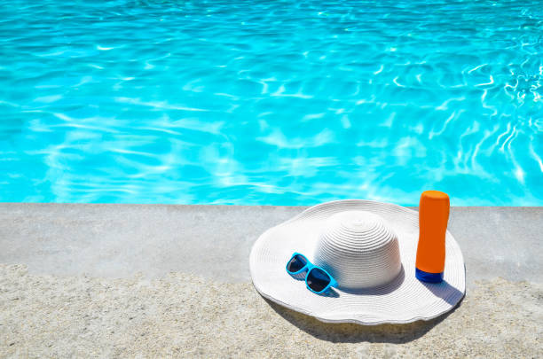 istock Summer hat, sunglasses and sunscreen near the pool 688337546