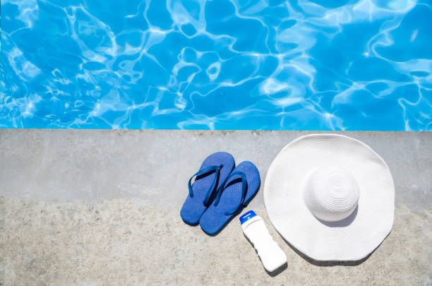 istock Summer background with hat, flip flops and sunscreen near the pool 688337992