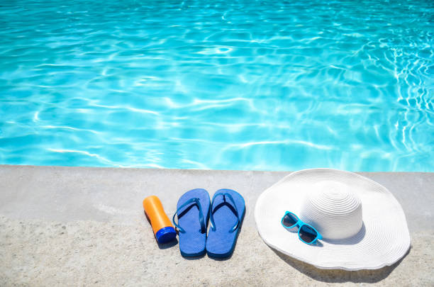 istock Summer background with hat, sunscreen, flip flops and sunglasses near the pool 688338012