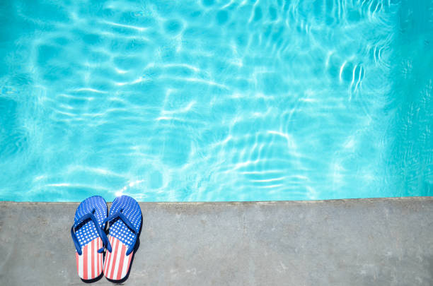 Summer background with flip flops near the pool Summer background with flip flops of American flag colors and pattern near the swimming pool usa flag shoes stock pictures, royalty-free photos & images