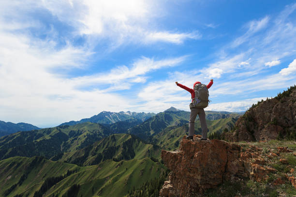 successful woman backpacker open arms on mountain peak
