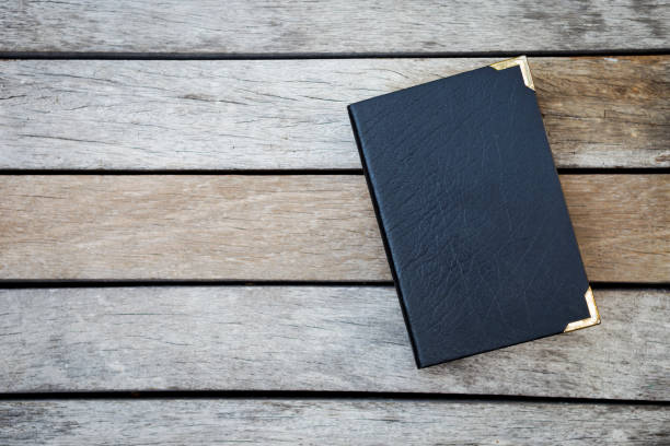 istock Old black leather cover book on wood background 688349176