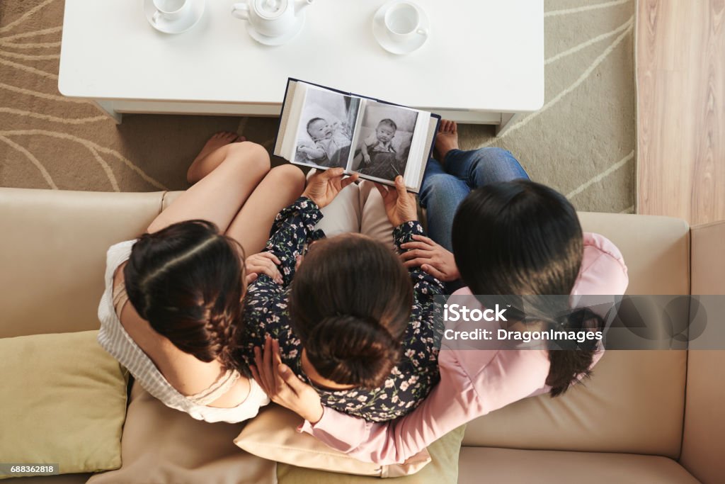 Watching baby photos Family watching old photos in album, view from above Nostalgia Stock Photo