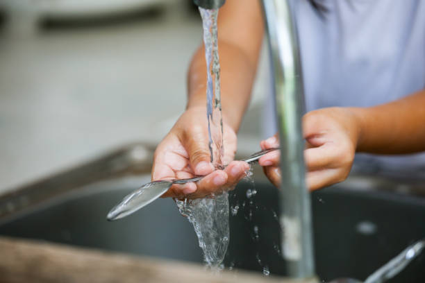 istock Child hand washing spoon over the sink in the kitchen 688376676