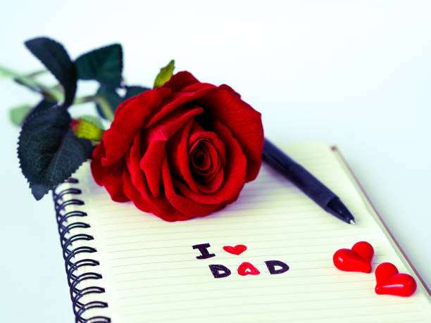 istock Father's day concept. I LOVE DAD message write on note book with red rose and pen on white background 688376814