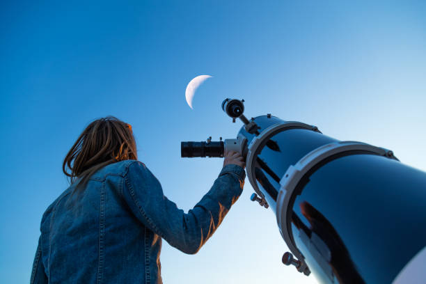 girl looking at the moon through a telescope. - eclipse imagens e fotografias de stock