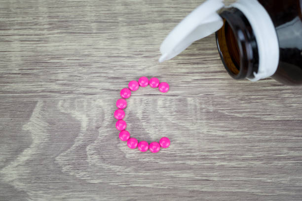 istock Pink pills forming shape to C alphabet on wood background 688390798