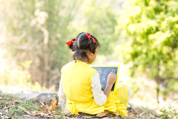 Rear view of Indian girl writing on slate