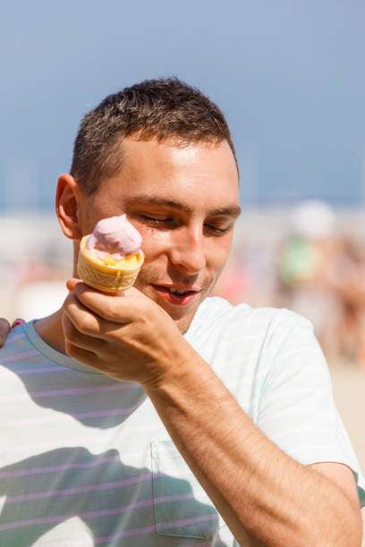istock Happy man eating ice cream on beach 688404212