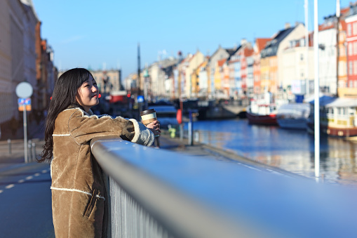Happy japanese woman tourist sightseeing in popular tourist area, Nyhavn, Copenhagen, Denmark. - February 15, 2017