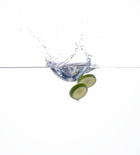 istock lime slices falling into the water on white background 688407564