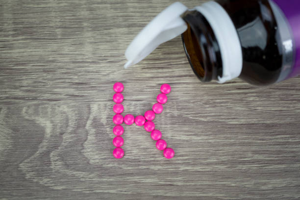 istock Pink pills forming shape to K alphabet on wood background 688407706