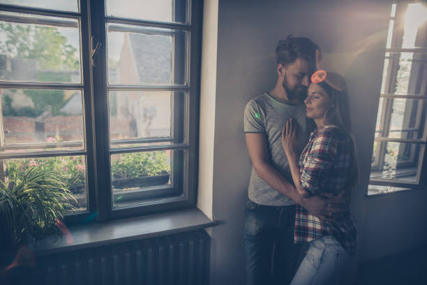 istock Young affectionate couple standing embraced with their eyes closed by the window. 688410368