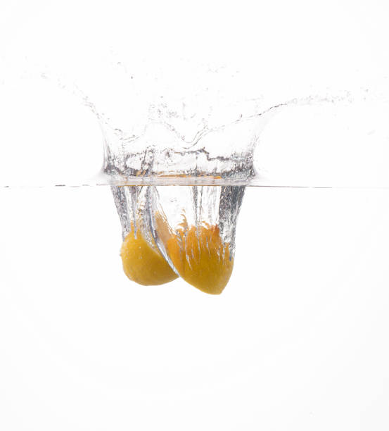 cut lemon falling into the water on white background