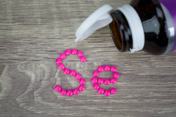 istock Pink pills forming shape to Se alphabet on wood background 688420398