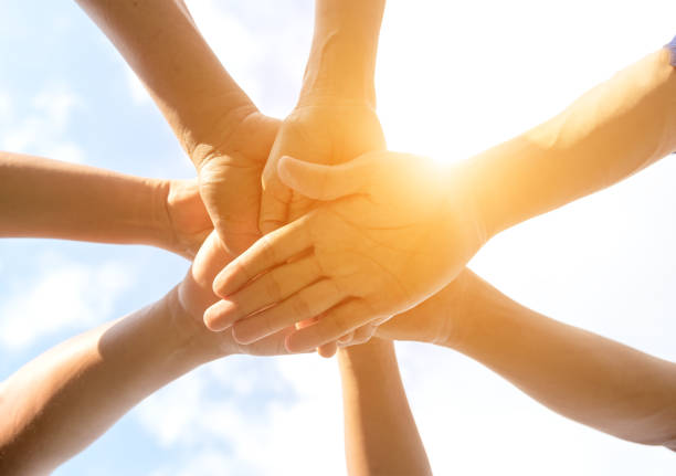 istock Hands of people team close up on blue sky background 688421778