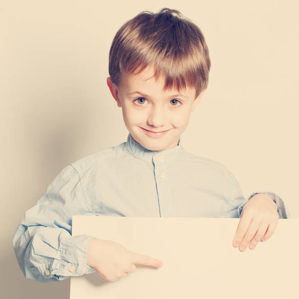 istock Smiling little boy with empty paper blank in hands 688424770