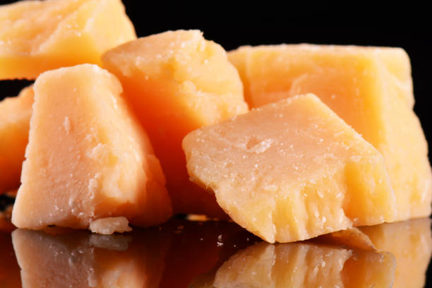 istock Parmesan cheese on a black glossy table with reflection. Parmesan cheese isolated on black background. 688424920