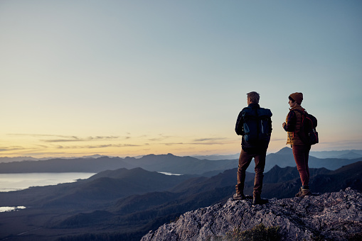Shot of two young hikers admiring the view from the top of a mountain together