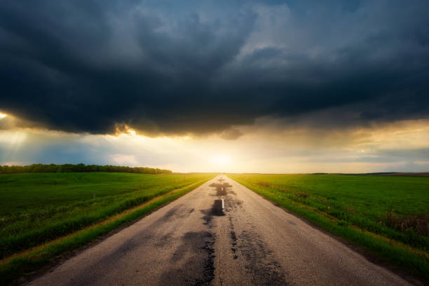 thunderstorm and heavy rain in a field above the road at a beautiful sunset in the summer, the problem of a slippery road