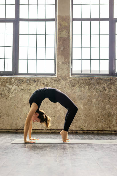 istock Young woman practicing yoga in urban loft: Upward Bow Pose 688445298