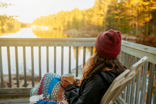 The view is definitely worth the stay Shot of a young woman relaxing by the lakeside cottage life stock pictures, royalty-free photos & images