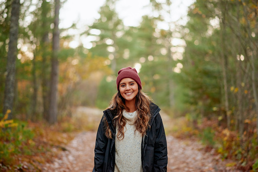 Young laughing woman holds yellow leaf in her hand in the park at sunset