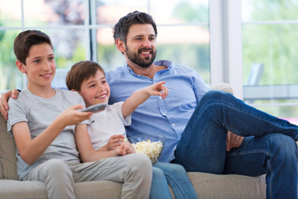 istock Father and sons watching tv at home 688455162