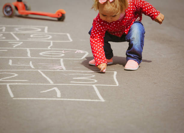 niña jugando hopscotch en el patio de recreo - little girls sidewalk child chalk fotografías e imágenes de stock