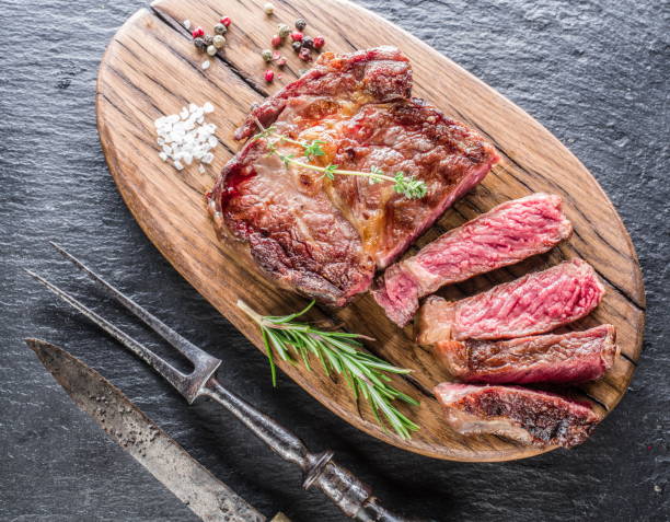 istock Medium Ribeye steak with spices on the wooden tray. 688458630