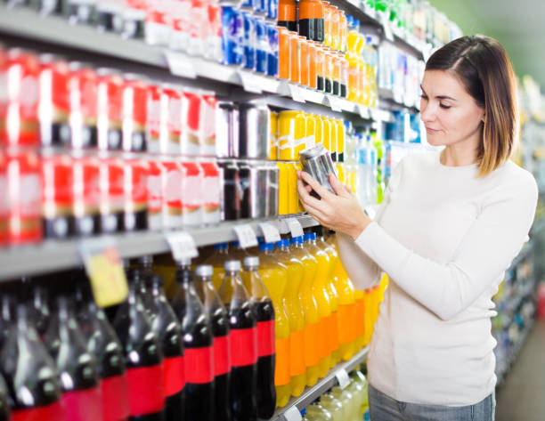 Girl customer looking for refreshing beverages Girl customer looking for refreshing beverages in supermarket non alcoholic beverage stock pictures, royalty-free photos & images