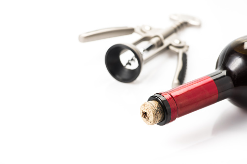 Top view of red wine glass stains with a vintage corkscrew and wine cork beside it shot on white background.