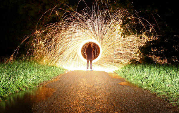 istock Man staring at spinning sparks and fire circle in road 688471206