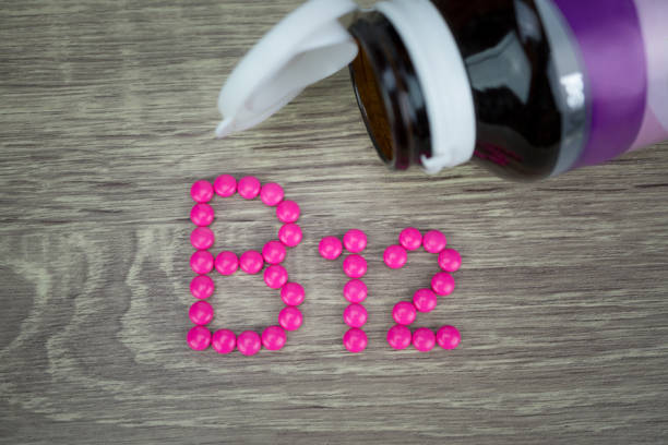 Pink pills forming shape to B12 alphabet on wood background Pink pills forming shape to B12 alphabet on wood background pallet industrial equipment photos stock pictures, royalty-free photos & images