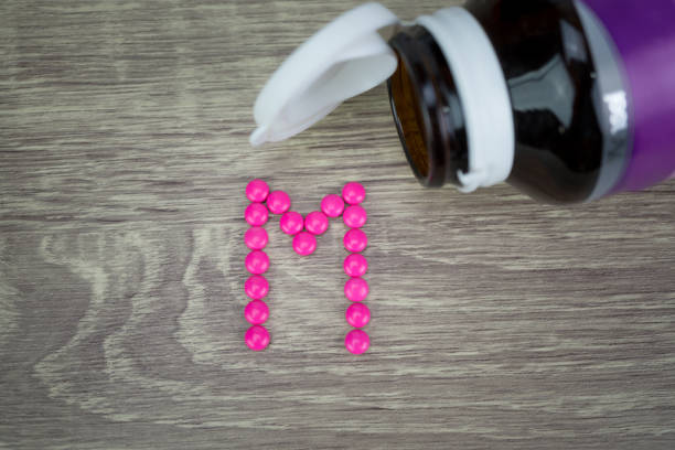 istock Pink pills forming shape to M alphabet on wood background 688474838