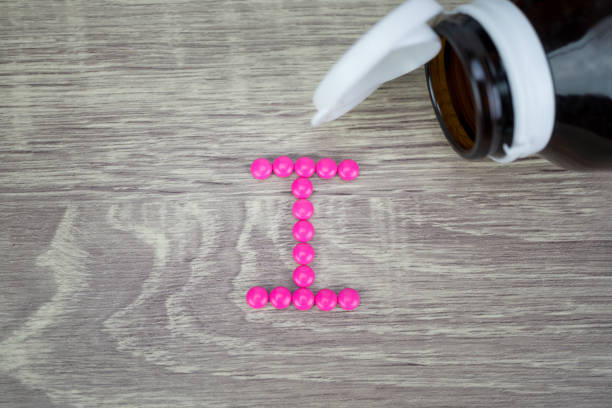 istock Pink pills forming shape to I alphabet on wood background 688475104